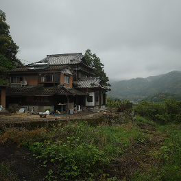 曇り空の下の古民家と山並み