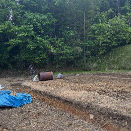 地面に掘られた溝と、その奥の竹林