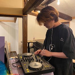 木の梁がある室内でDJ機材を操作する人