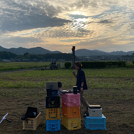 山並みと夕空、畑に並べられたコンテナ